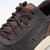 Close-up of a brown leather sneaker with brown laces on a light gray background
