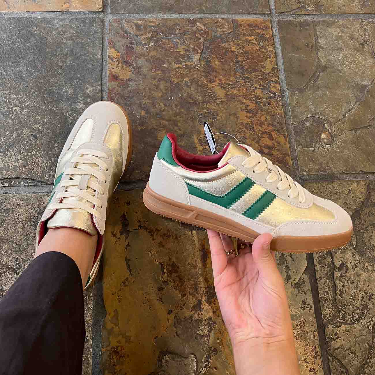 Person holding a green and beige sneaker against a tiled wall background