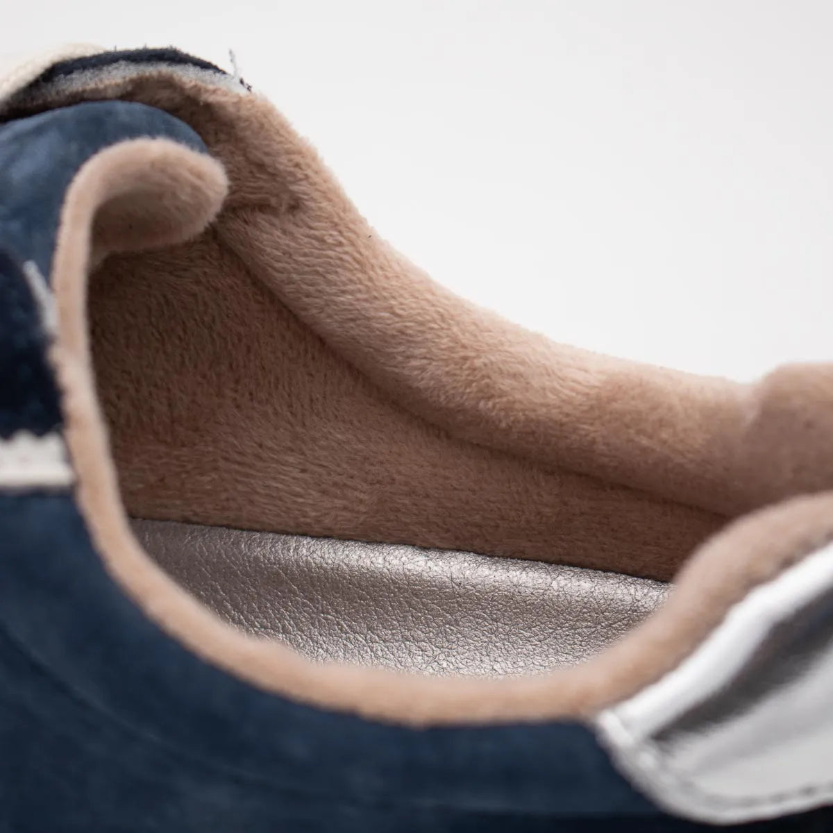 Close-up of a brown leather shoe with a white sole on a light gray background