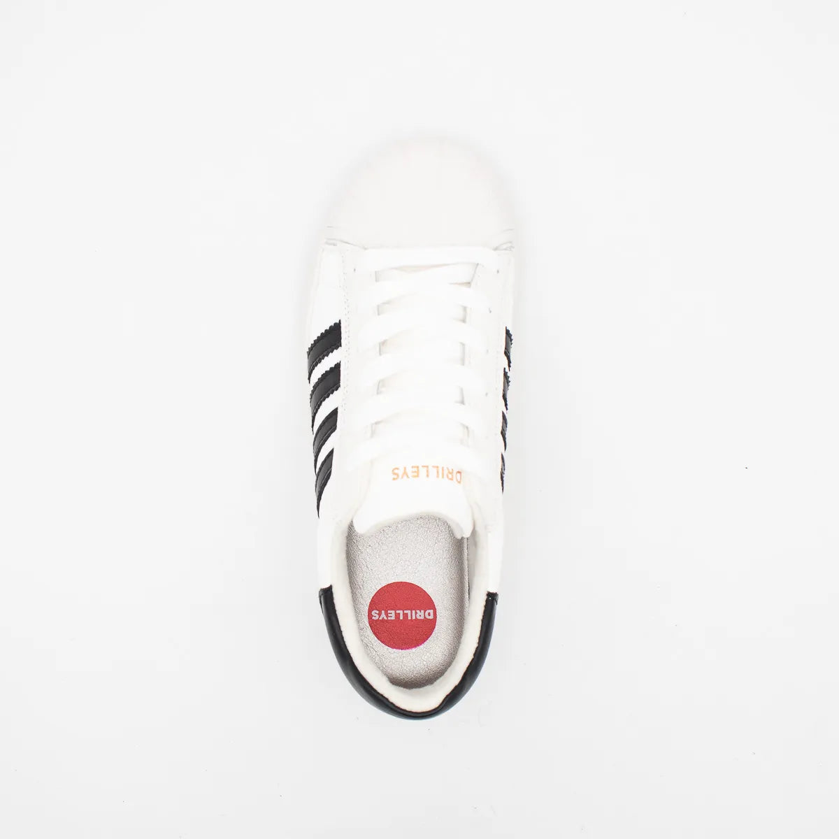 White sneaker with black stripes and red logo on a white background