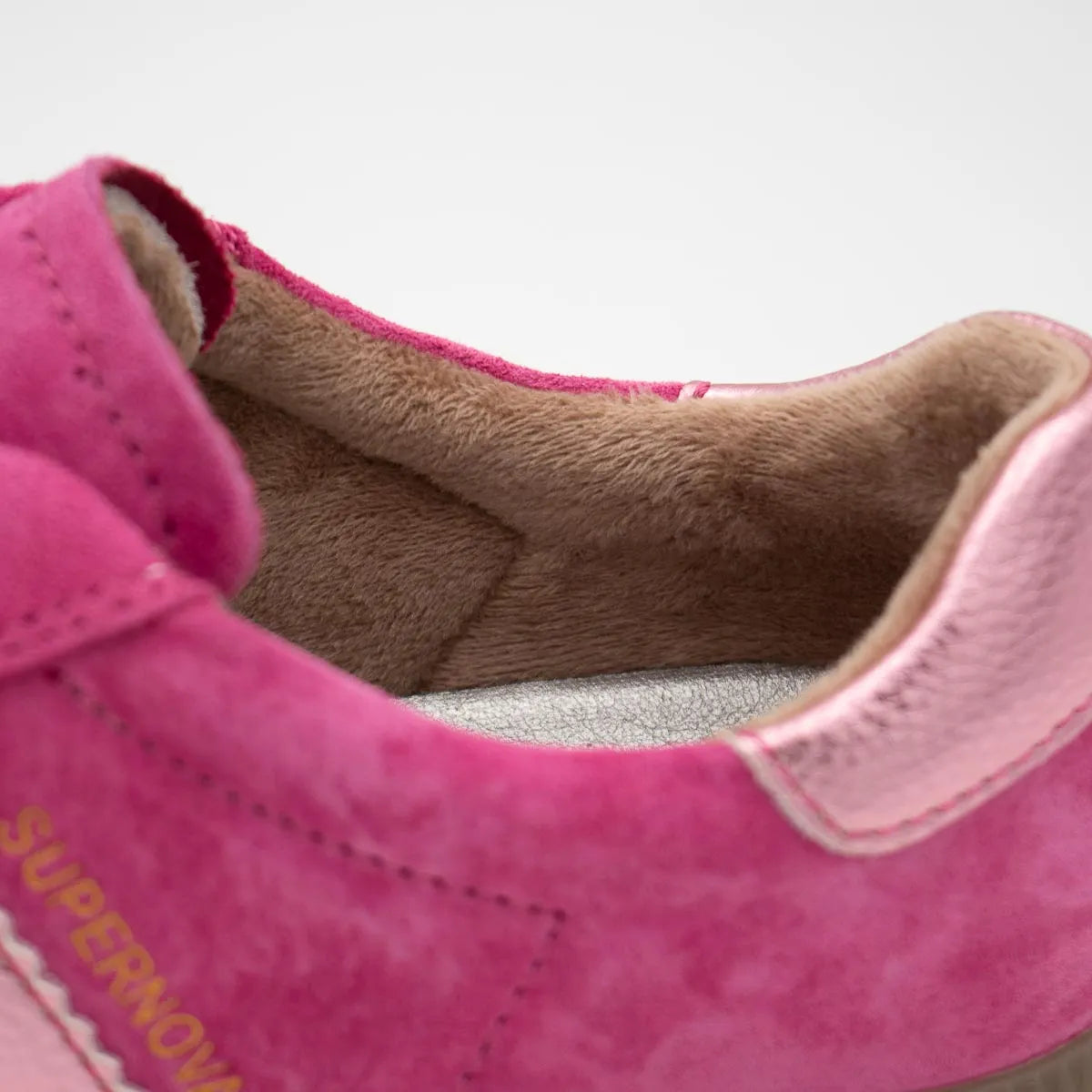 Close-up of a pink shoe with brown lining on a white background