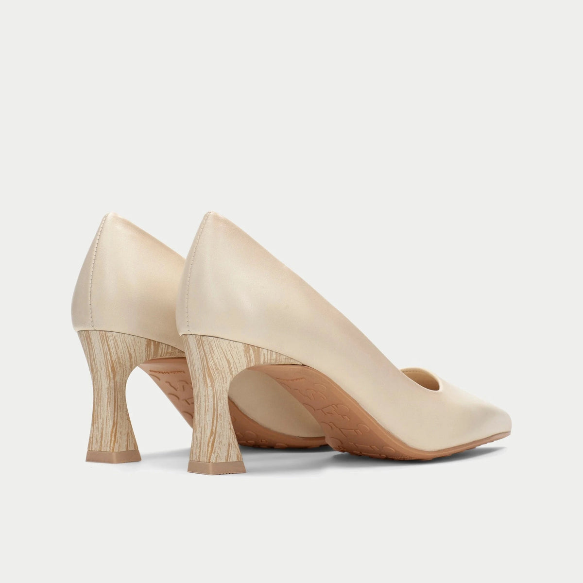 Pair of beige high-heeled shoes on a light gray background
