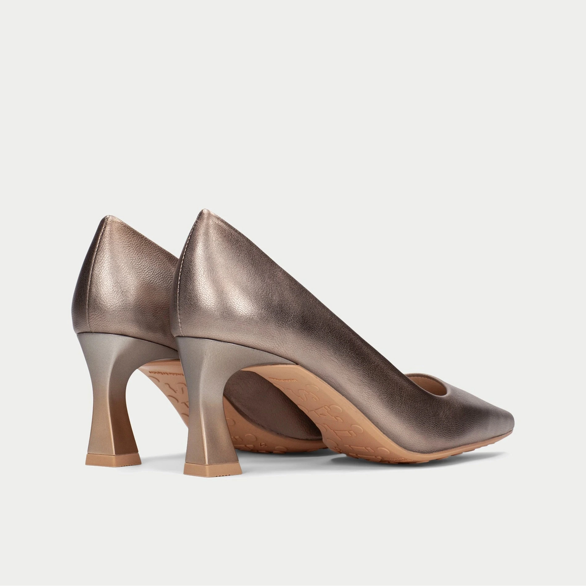 Pair of bronze high-heeled shoes on a light gray background