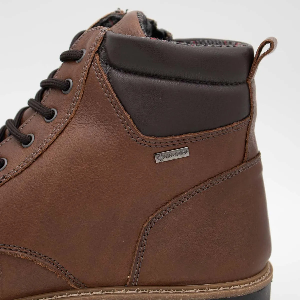 Close-up of a brown leather boot with a visible brand logo on a light gray background