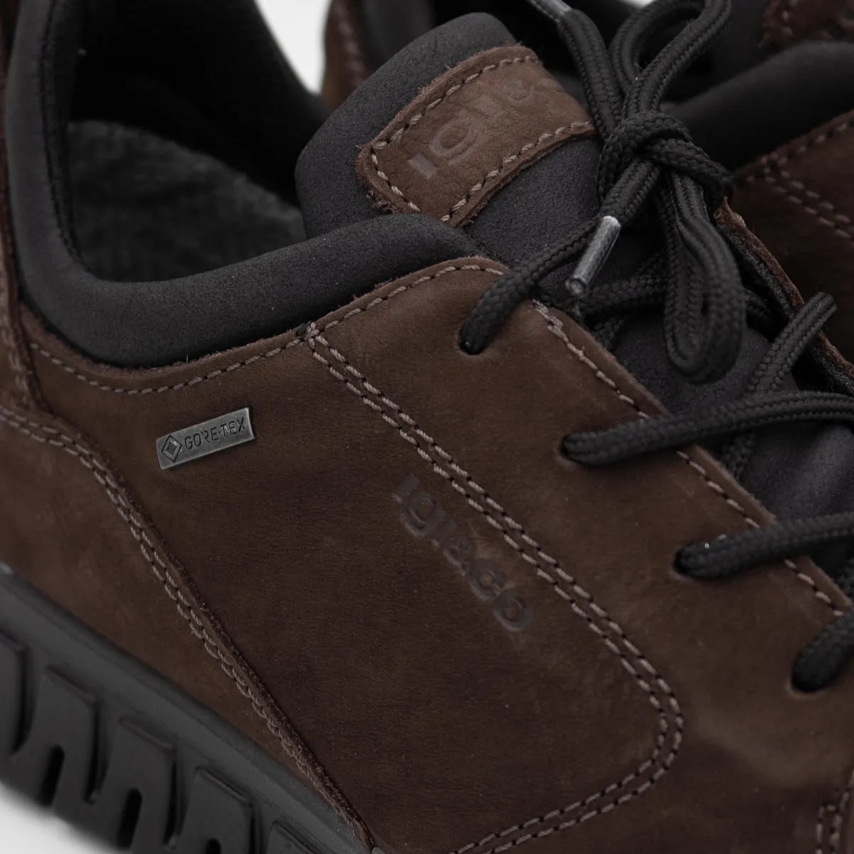 Close-up of a brown leather shoe with black laces and a visible brand logo.