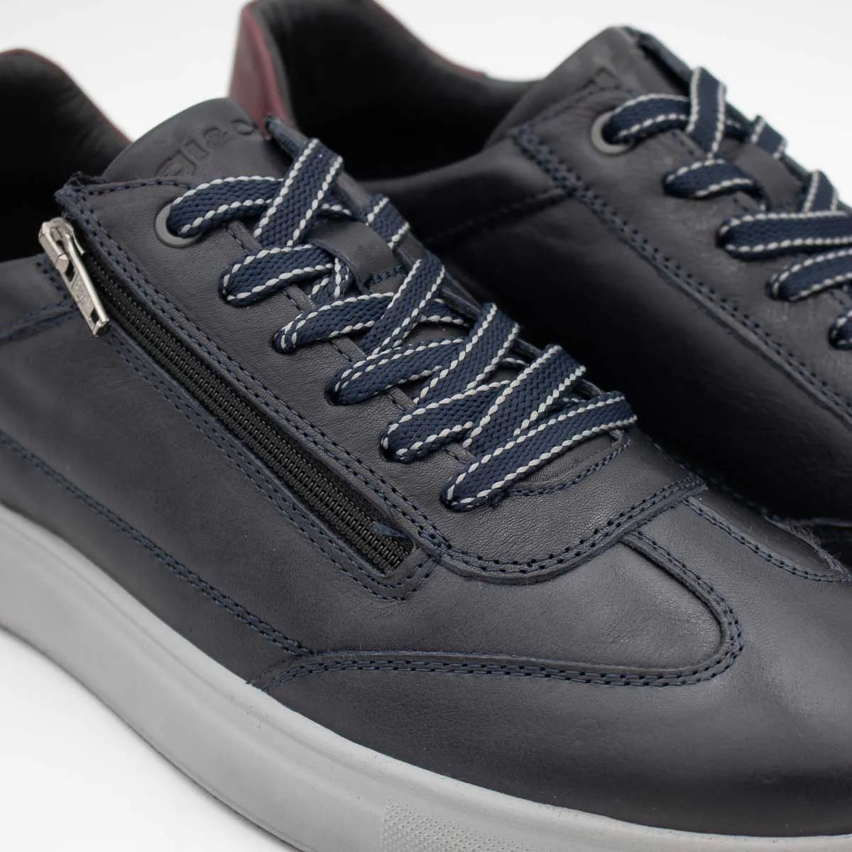 Dark gray sneakers with navy laces and a zipper on a light gray background