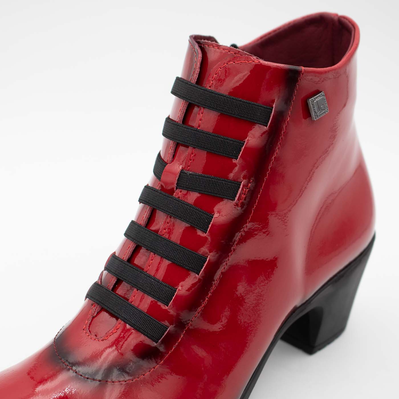 Side profile of Jose Saenz's glossy red patent ankle boot.