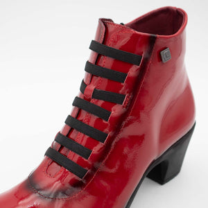 Detailed view of the elasticated bungee lace on red patent boot.
