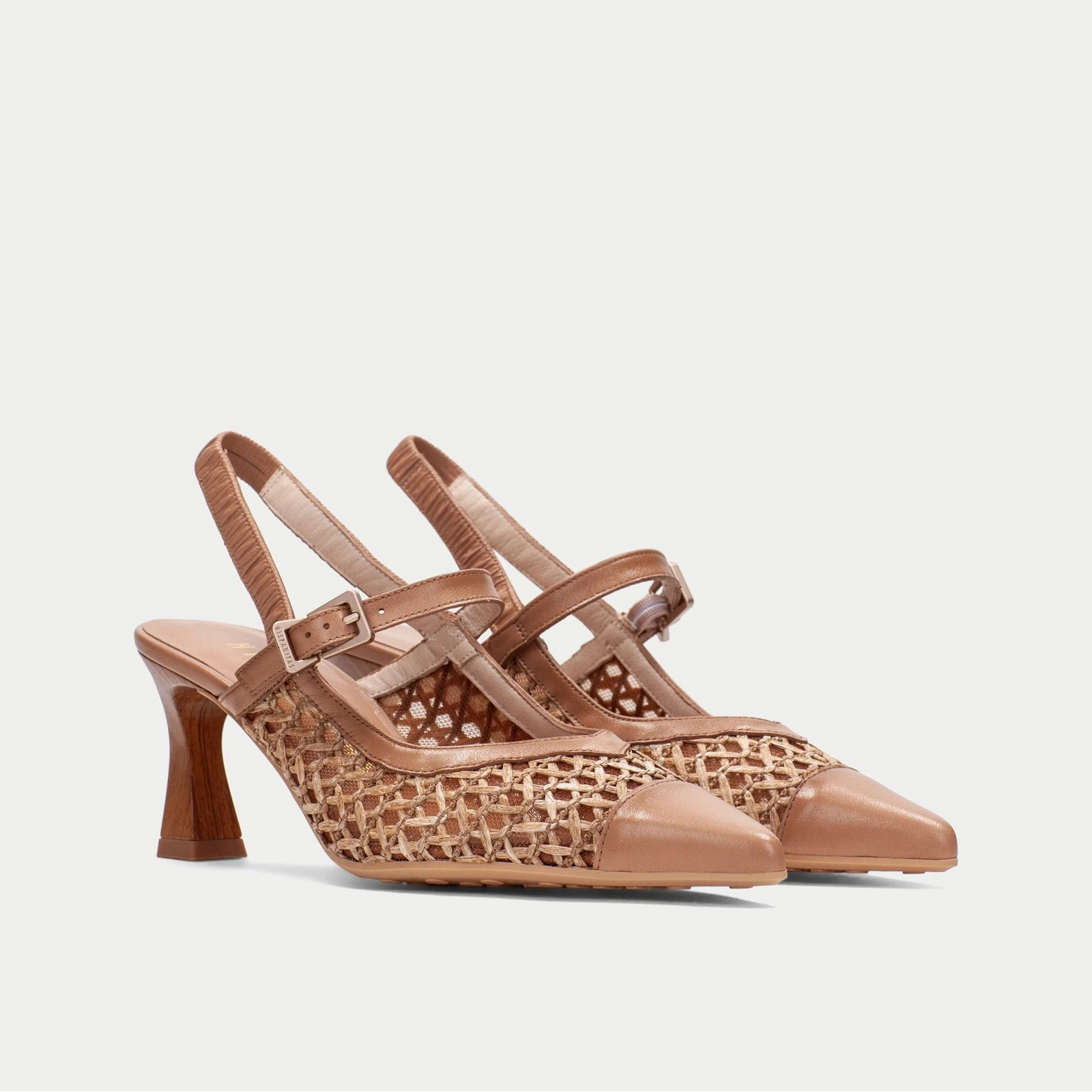 Pair of tan high-heeled shoes with woven design on a light gray background