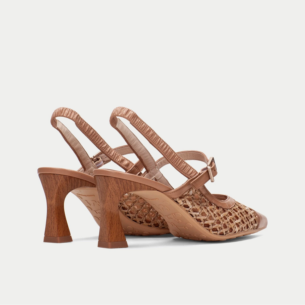 Pair of brown open-toe high-heeled shoes with wooden heel on a light gray background