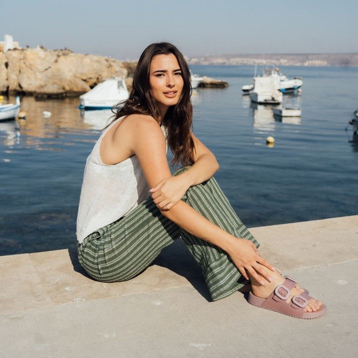 Woman sitting by a waterfront with boats and a clear sky