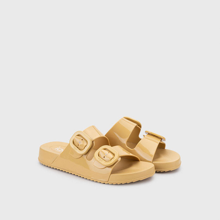 Pair of yellow sandals with buckle straps on a light gray background