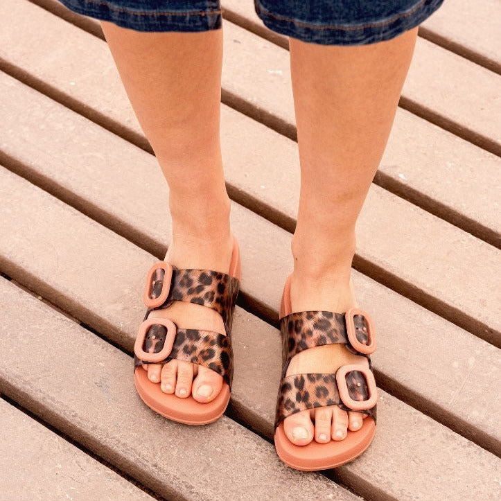 Person wearing leopard print sandals on a wooden floor