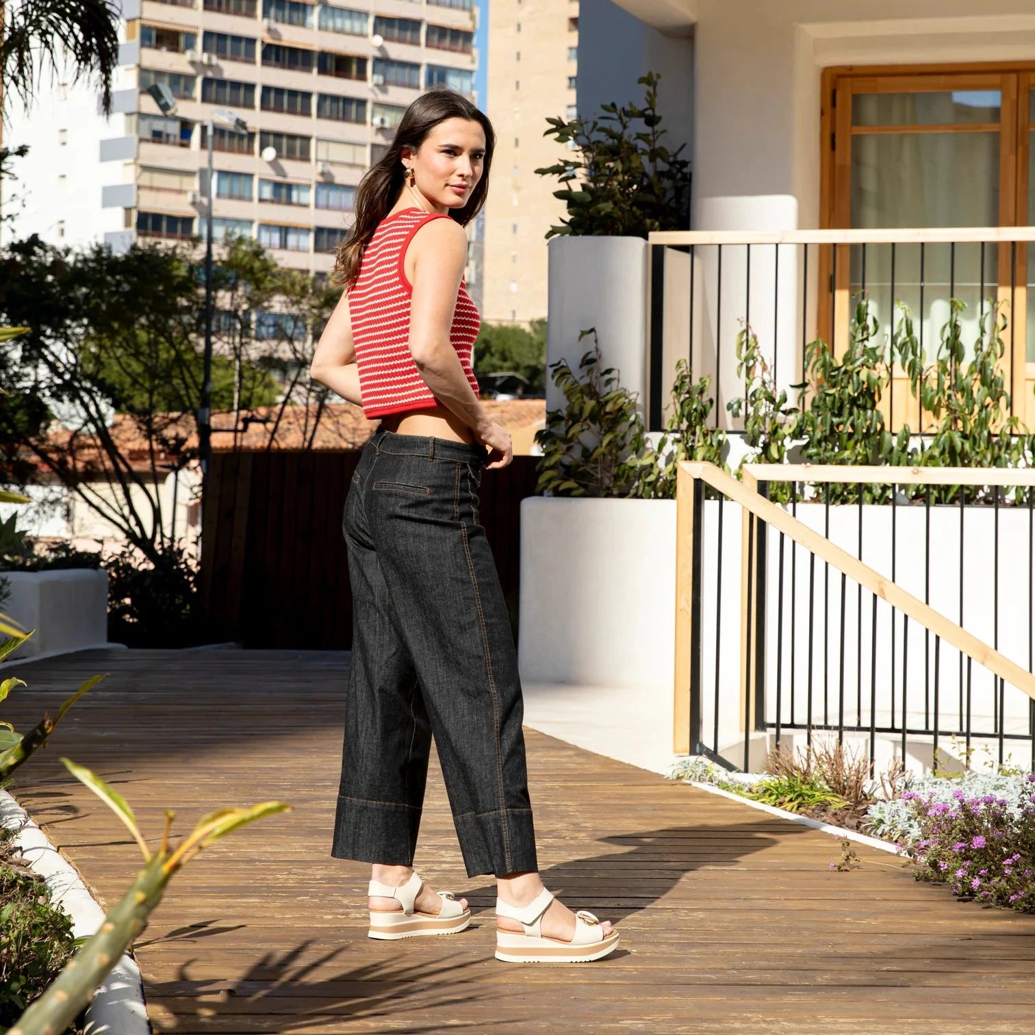 Woman standing on a wooden deck with modern buildings in the background