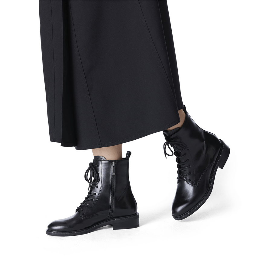 Woman wearing the lace-up black ankle boots with a skirt