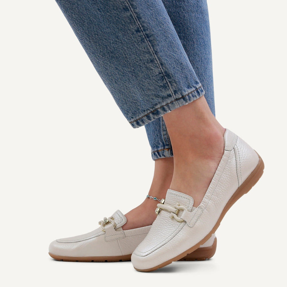 White loafers worn with blue jeans on a white background