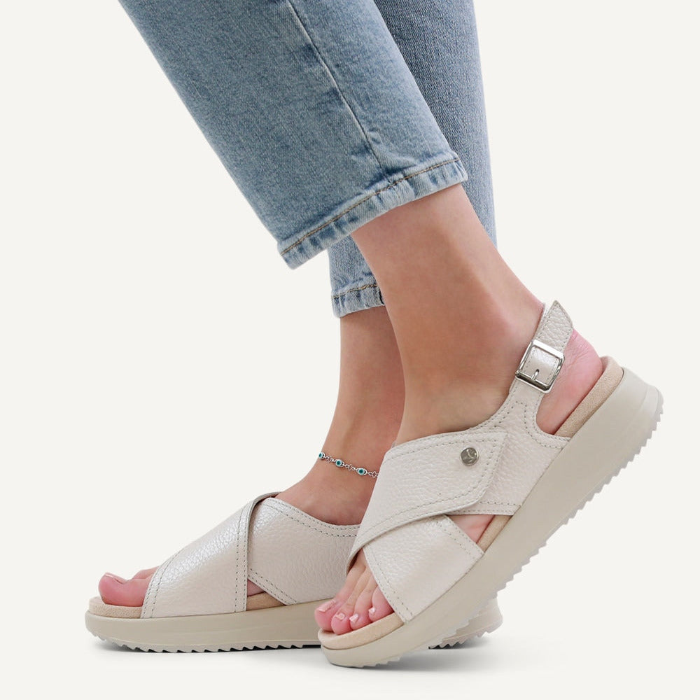 White sandals with pink soles worn with light blue jeans on a white background