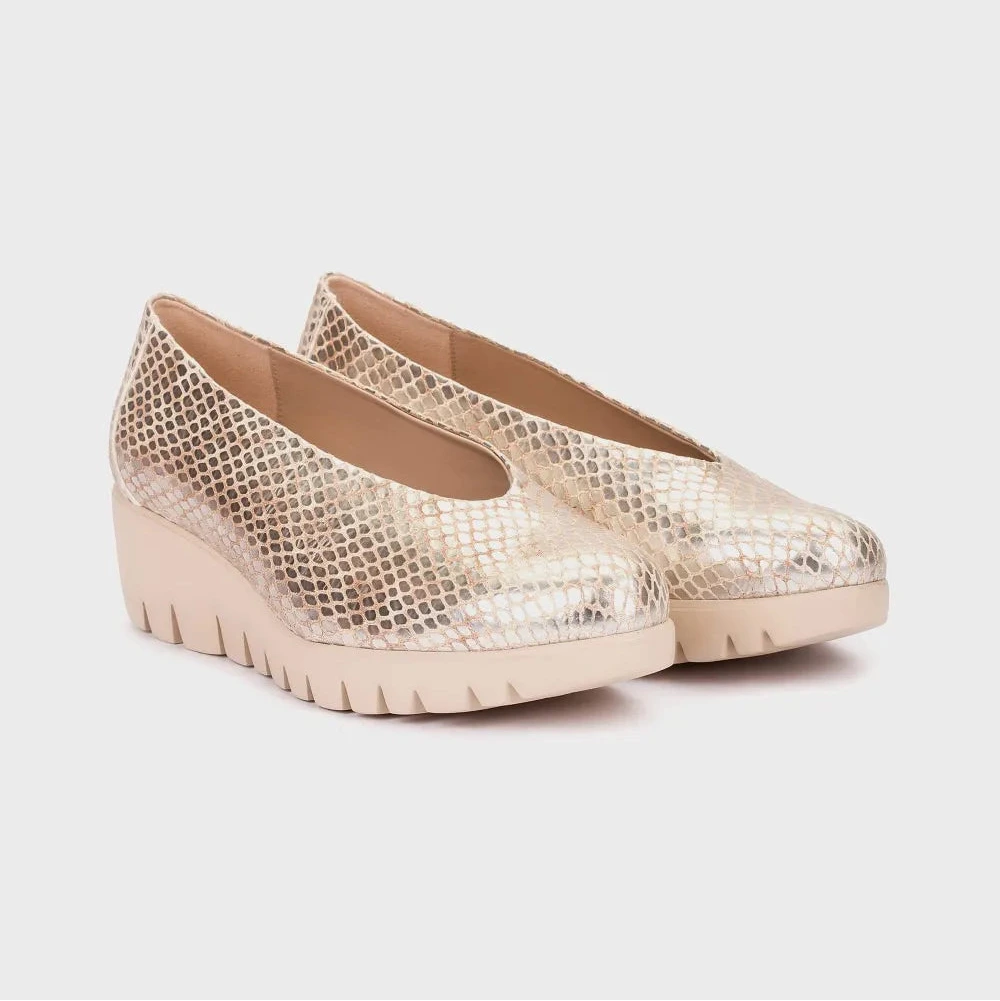 Pair of gold wedge shoes on a light gray background