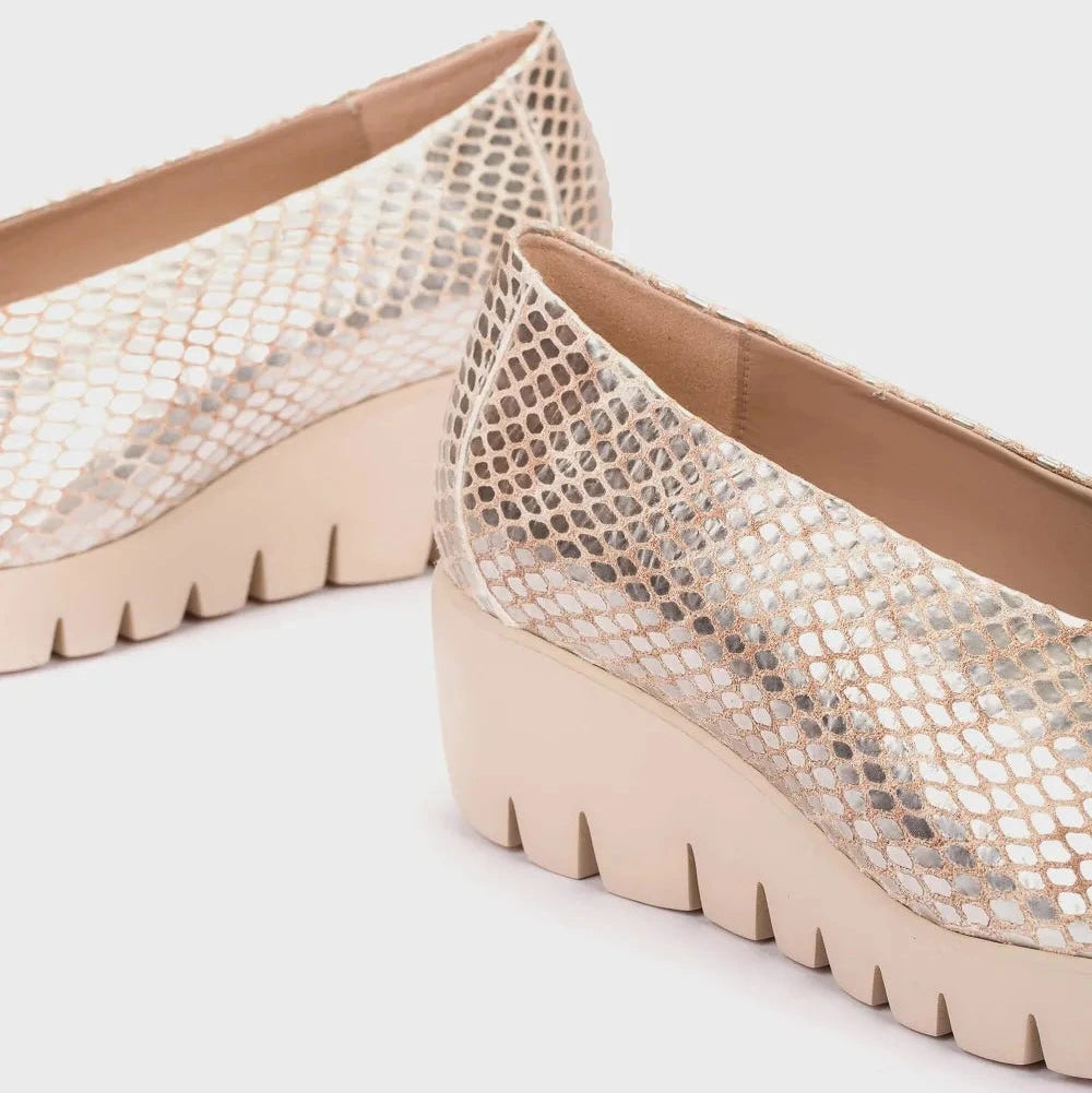 Beige wedge shoes with snake print pattern on a light gray background
