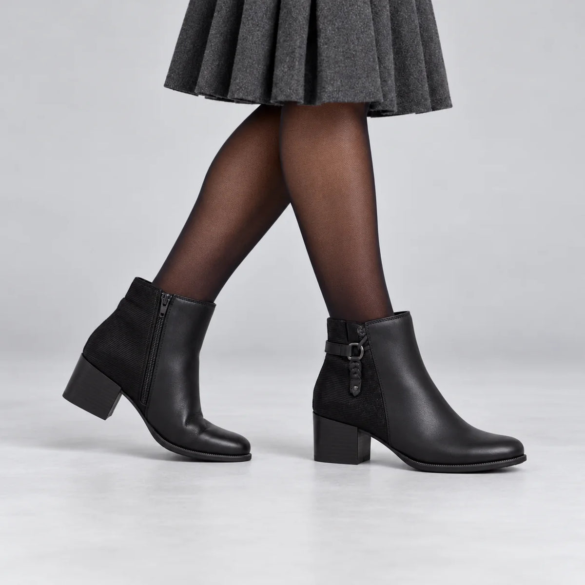 Dubarry Cynthia black leather ankle boots styled with a charcoal skirt and tights, showing the inside zip on the left boot in a grey studio