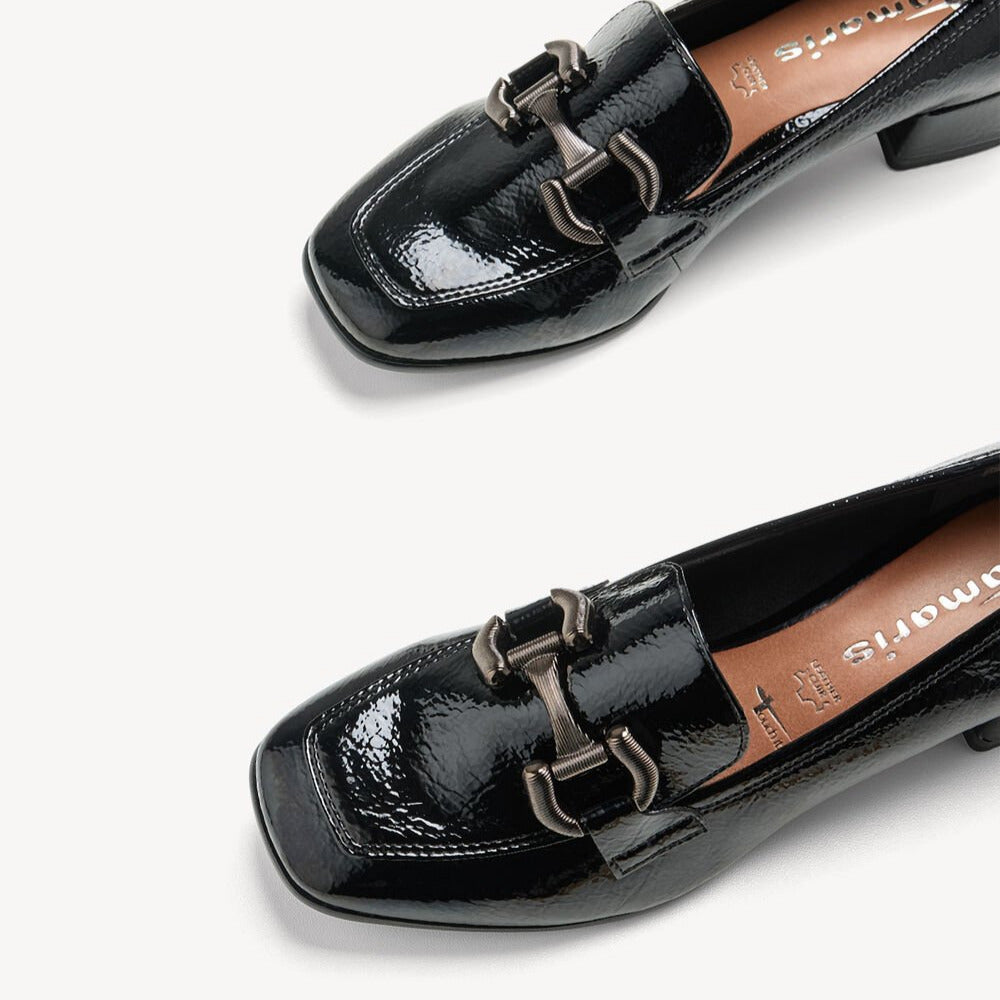 Black patent leather loafers with a decorative buckle on a white background