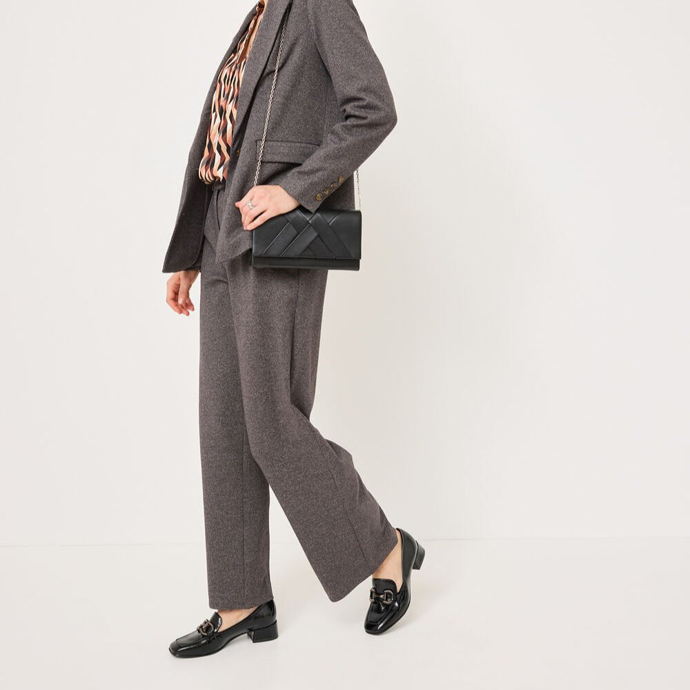 Woman wearing a gray suit with a black clutch on a white background