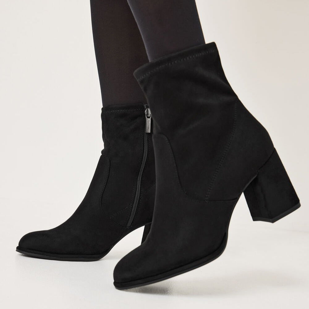 Black ankle boots worn with tights on a light gray background