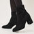 Black ankle boots worn with tights on a light gray background