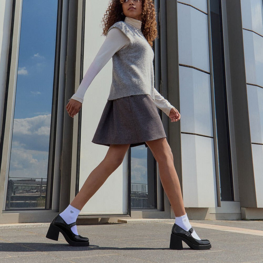 Black platform shoes worn with gray jeans on a white background