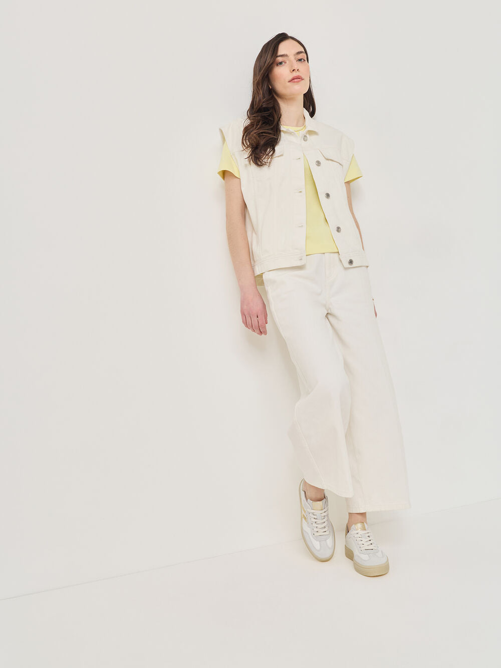 Woman wearing a light yellow top and pants with a white background