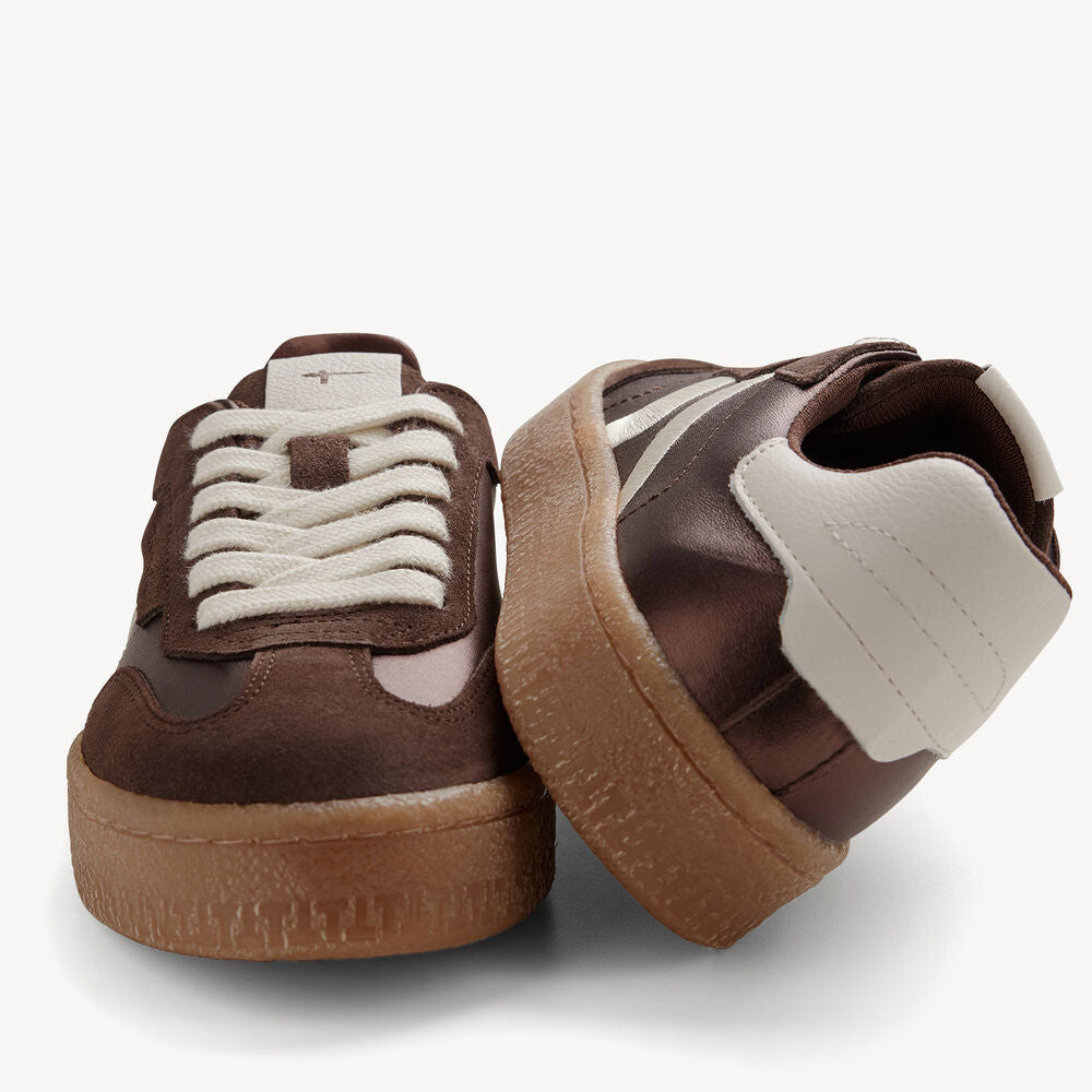 Pair of brown sneakers with white laces on a light gray background