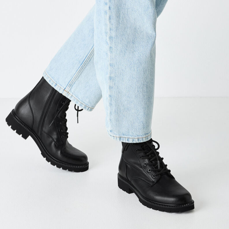 Black boots worn with light blue jeans on a white background