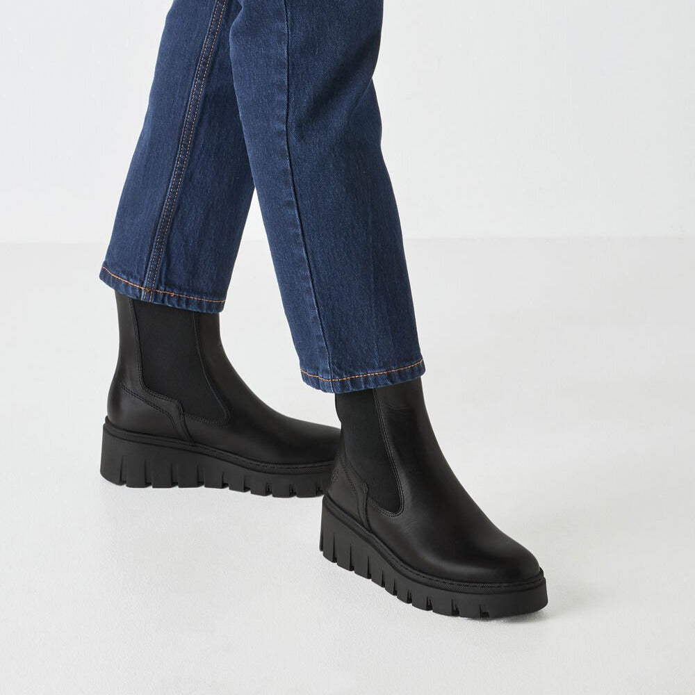 Black chunky boots worn with blue jeans on a white background