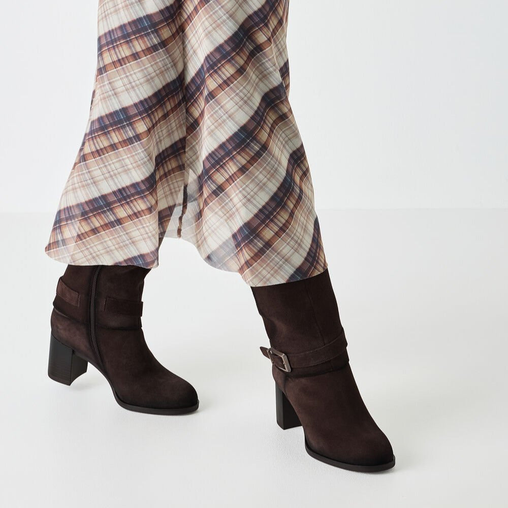 Brown suede boots worn with plaid pants on a white background