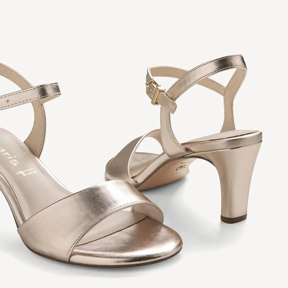 Pair of gold high-heeled sandals on a white background