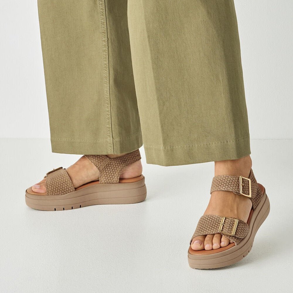 Brown sandals worn with green pants on a white background