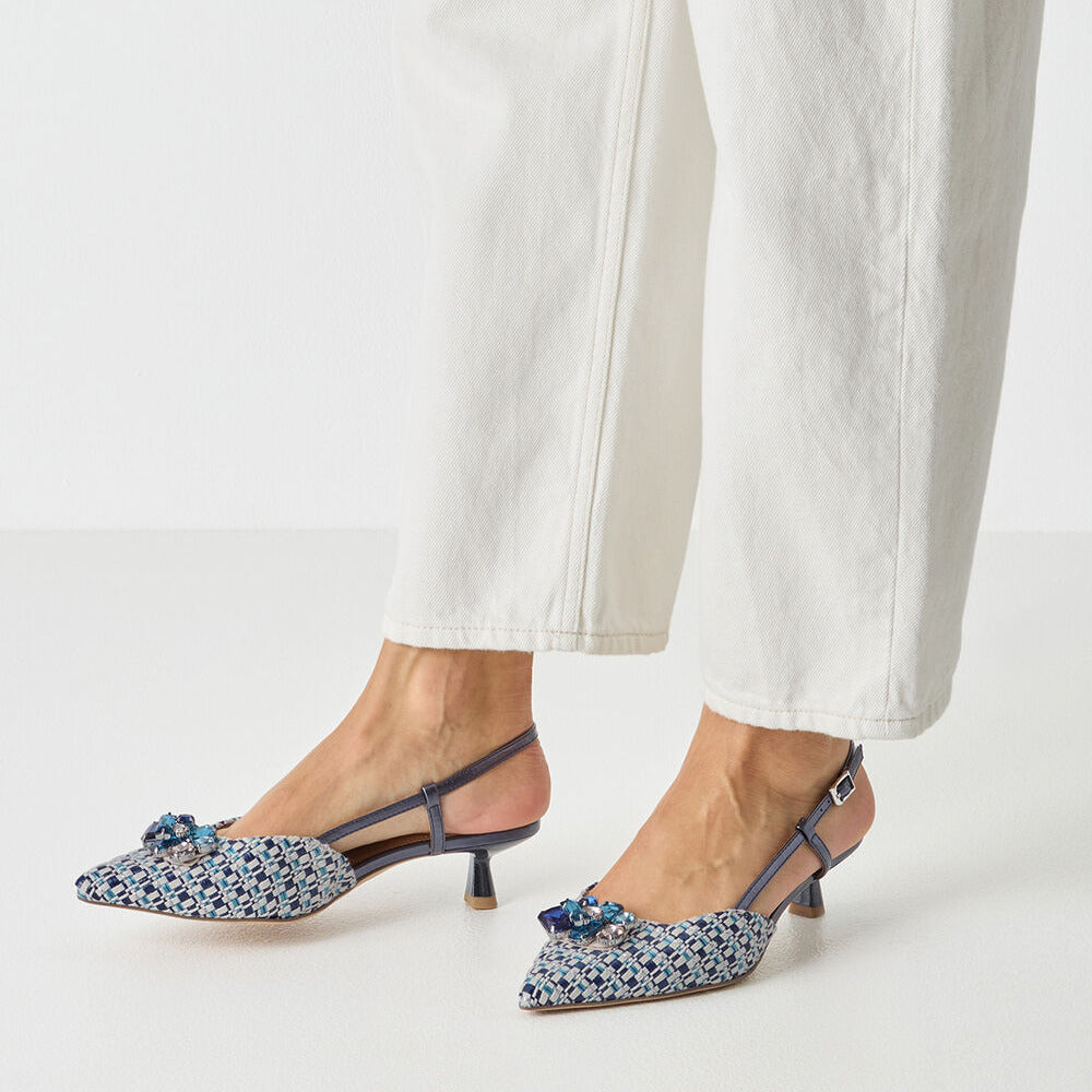 Blue floral shoes worn with white pants on a light gray background