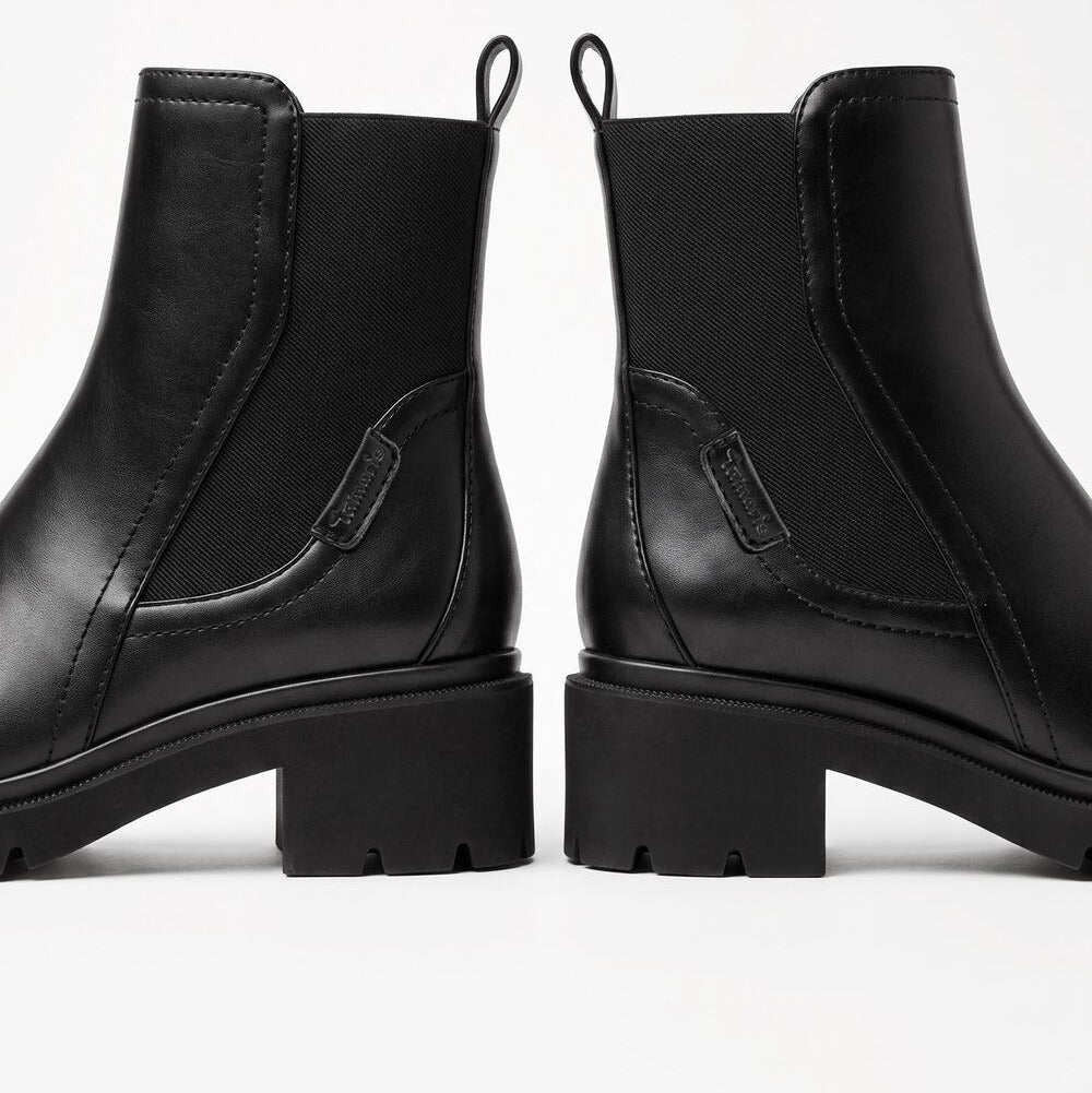 A pair of black leather Chelsea-style ankle boots with elastic side panels and chunky lug soles, shown from the back on a clean white studio background.