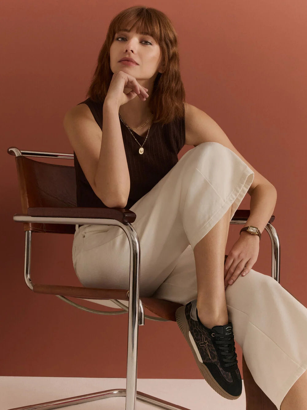 Woman sitting on a chair against a red-brown background