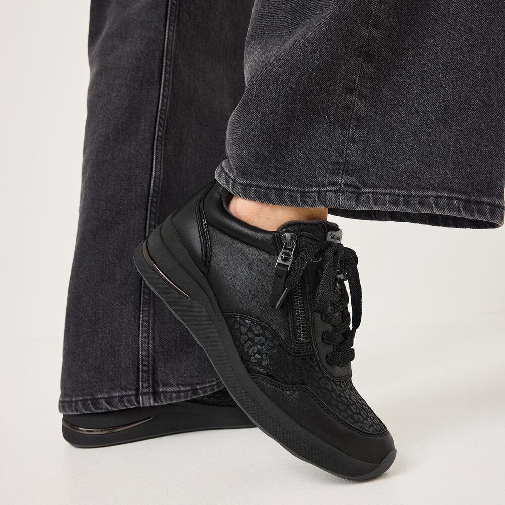 Black high-top sneakers worn with black jeans on a light gray background