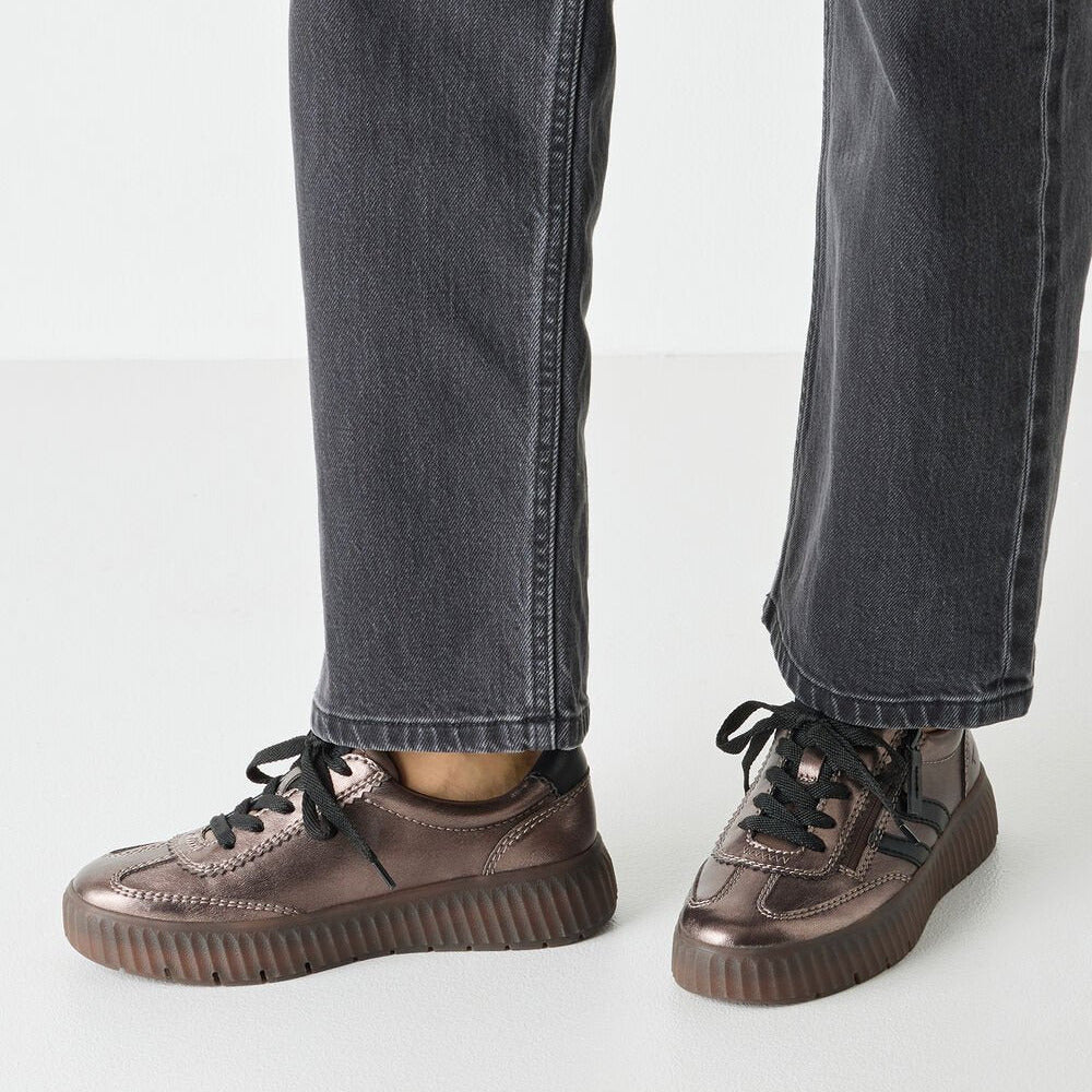 Brown sneakers worn with black jeans on a white background