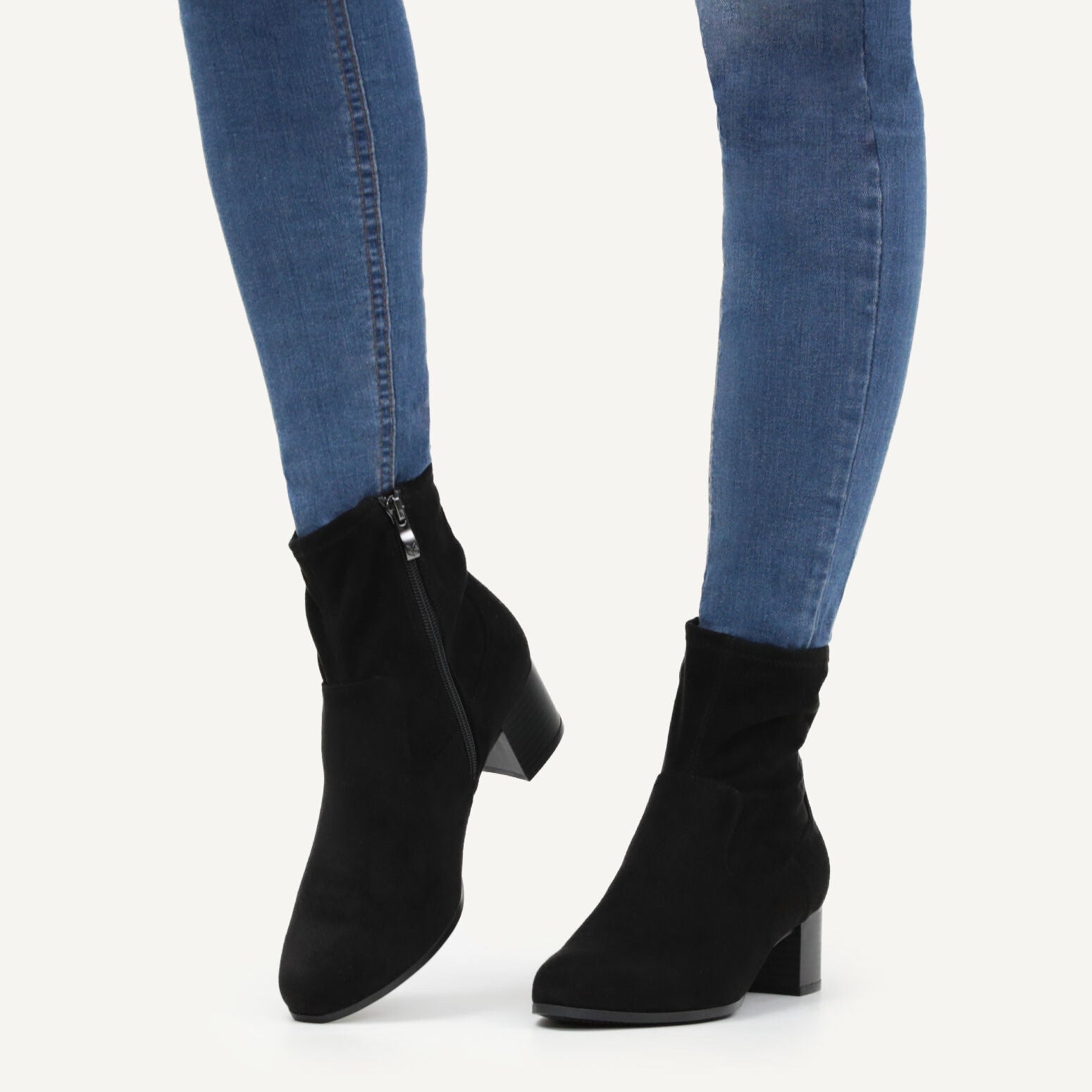 Black ankle boots worn with blue jeans on a white background