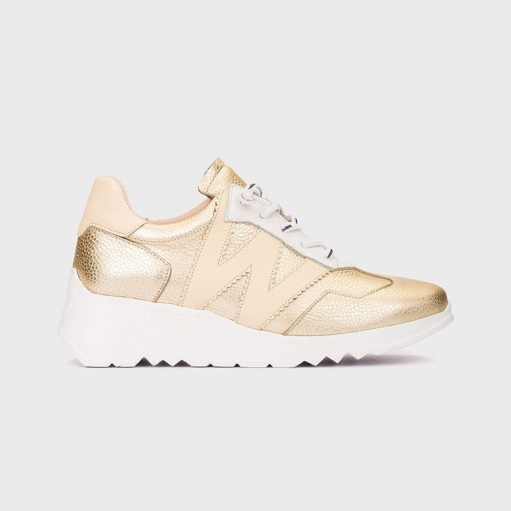 Gold sneaker with white sole on a light gray background