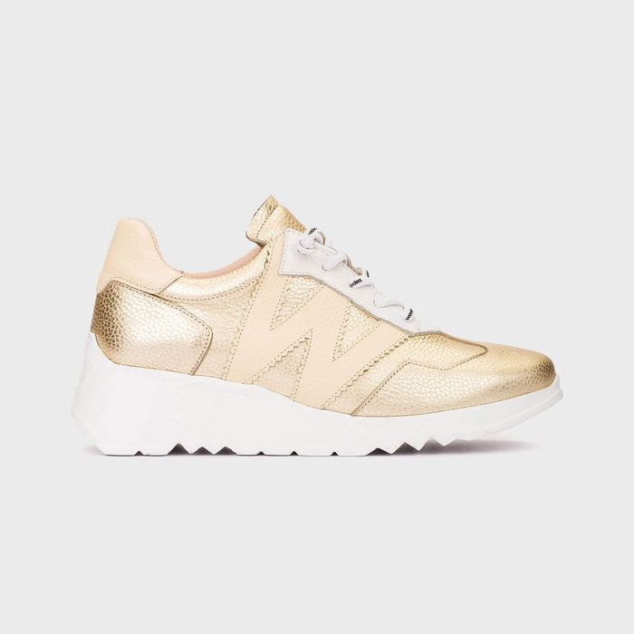 Gold sneaker with white sole on a light gray background