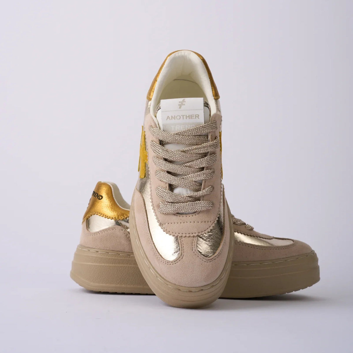 Beige sneakers with gold accents on a light gray background