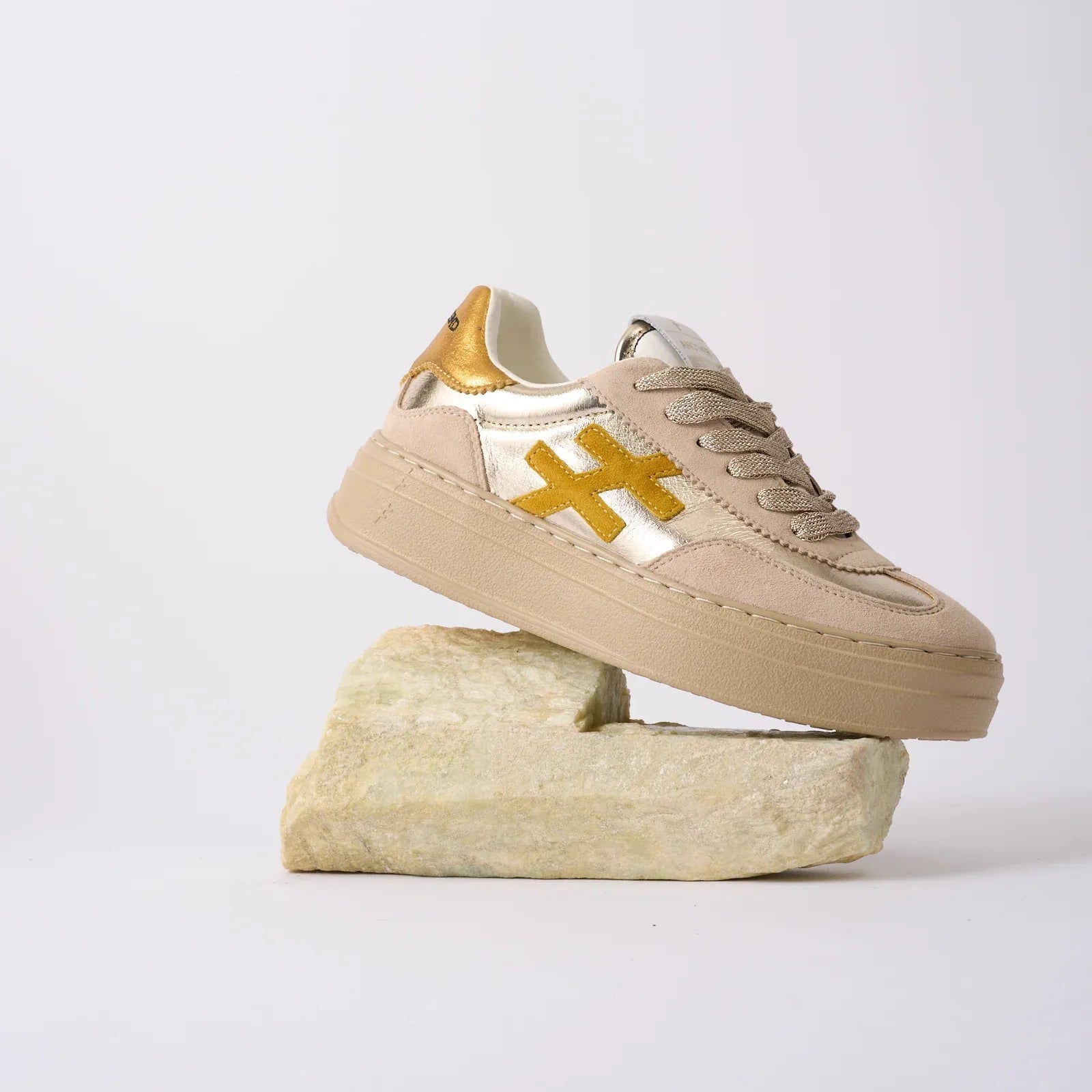Beige sneaker with gold accents on a white background