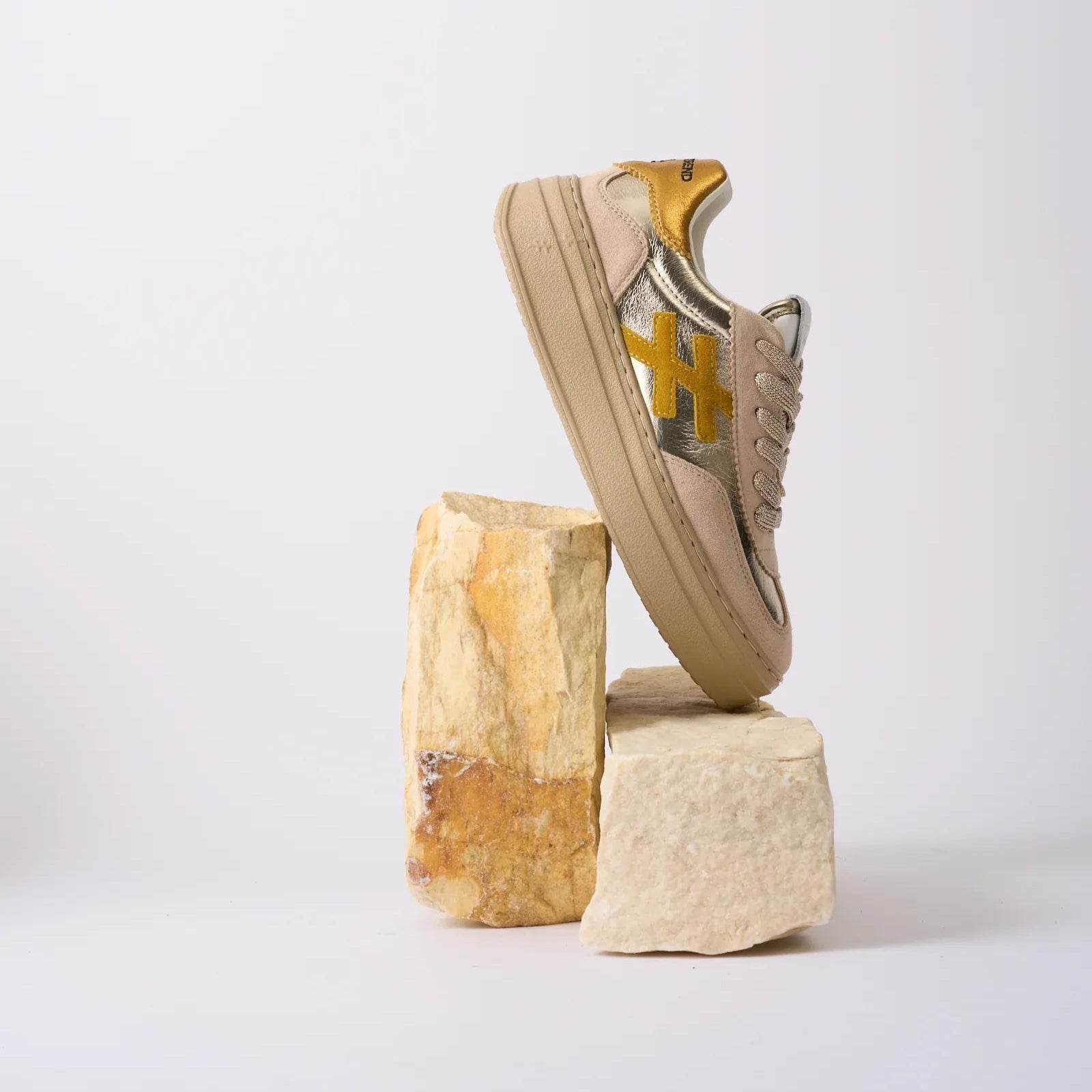 Beige sneaker with gold accents on a white background