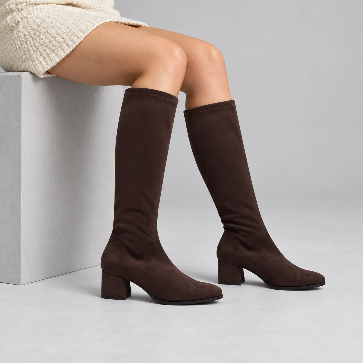Miss Elastic Dark Brown Suede-Effect Stretch Knee-High Boots worn by a female model in a neutral grey studio