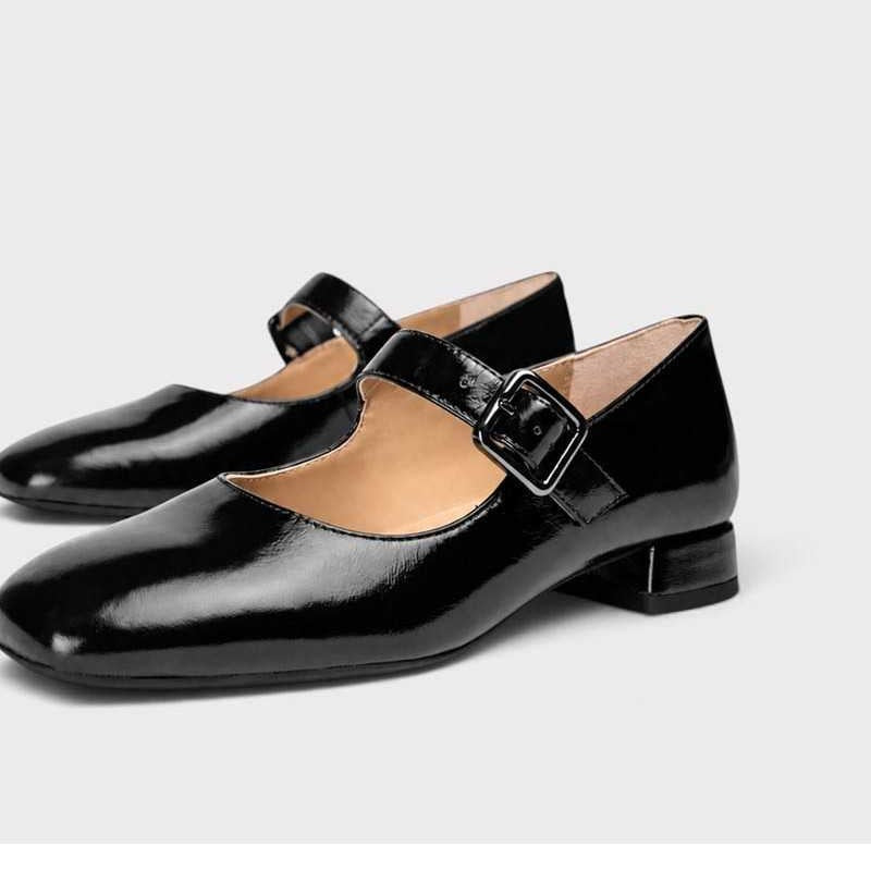 Close-up of Unisa Culver black patent leather Mary Jane shoes showing the buckle straps and glossy finish