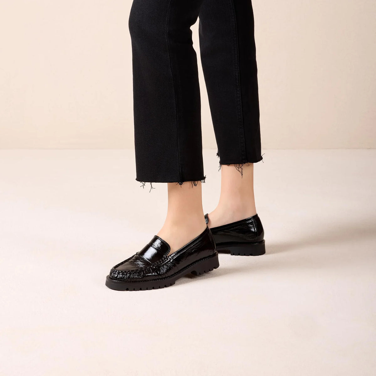 Unisa Fijo black patent loafers worn with cropped black trousers in the brand's studio photograph.